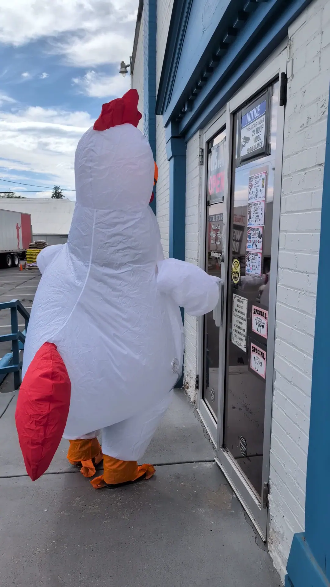 Person in an inflatable chicken costume at the store door