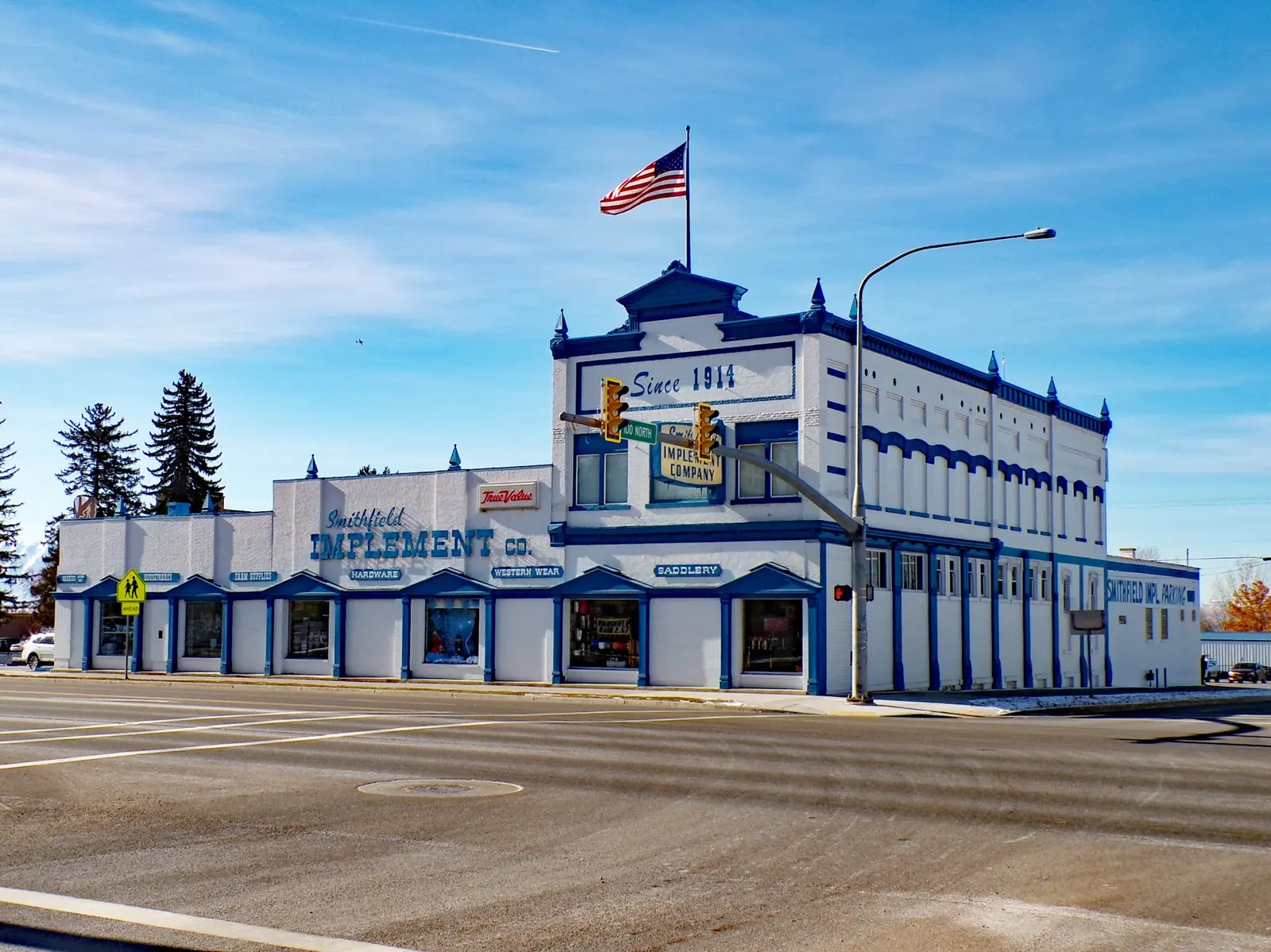 The corner storefront of Smithfield Implement under a flag and blue sky